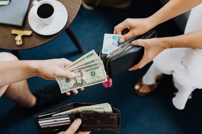 people looking at their wallets' contents